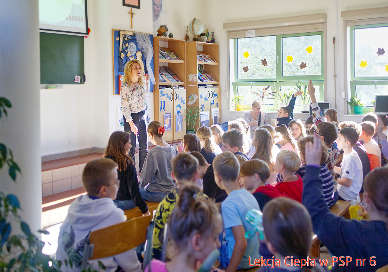 Pracownik „RADPEC” S.A. prowadzi lekcję ciepła dla uczniów klasy IV PSP nr 6. Stoi przed grupą uczniów. W tle znajduje się ekran z jednym ze slajdów prezentacji.