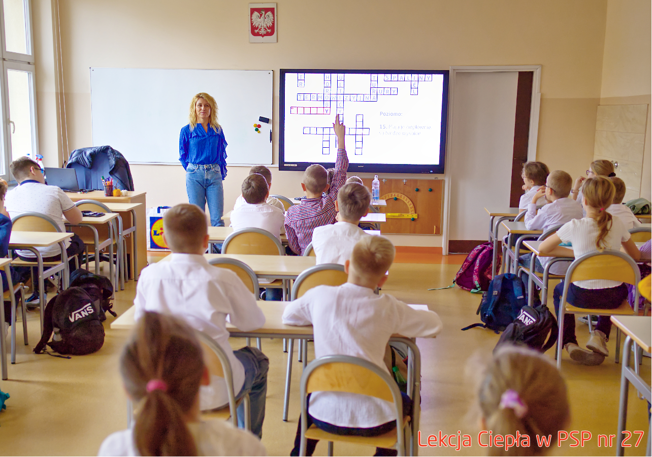 Pracownik „RADPEC” S.A. prowadzi lekcję ciepła dla uczniów klasy IV PSP nr 27. Stoi przed grupą uczniów. W tle znajduje się ekran z jednym ze slajdów prezentacji.