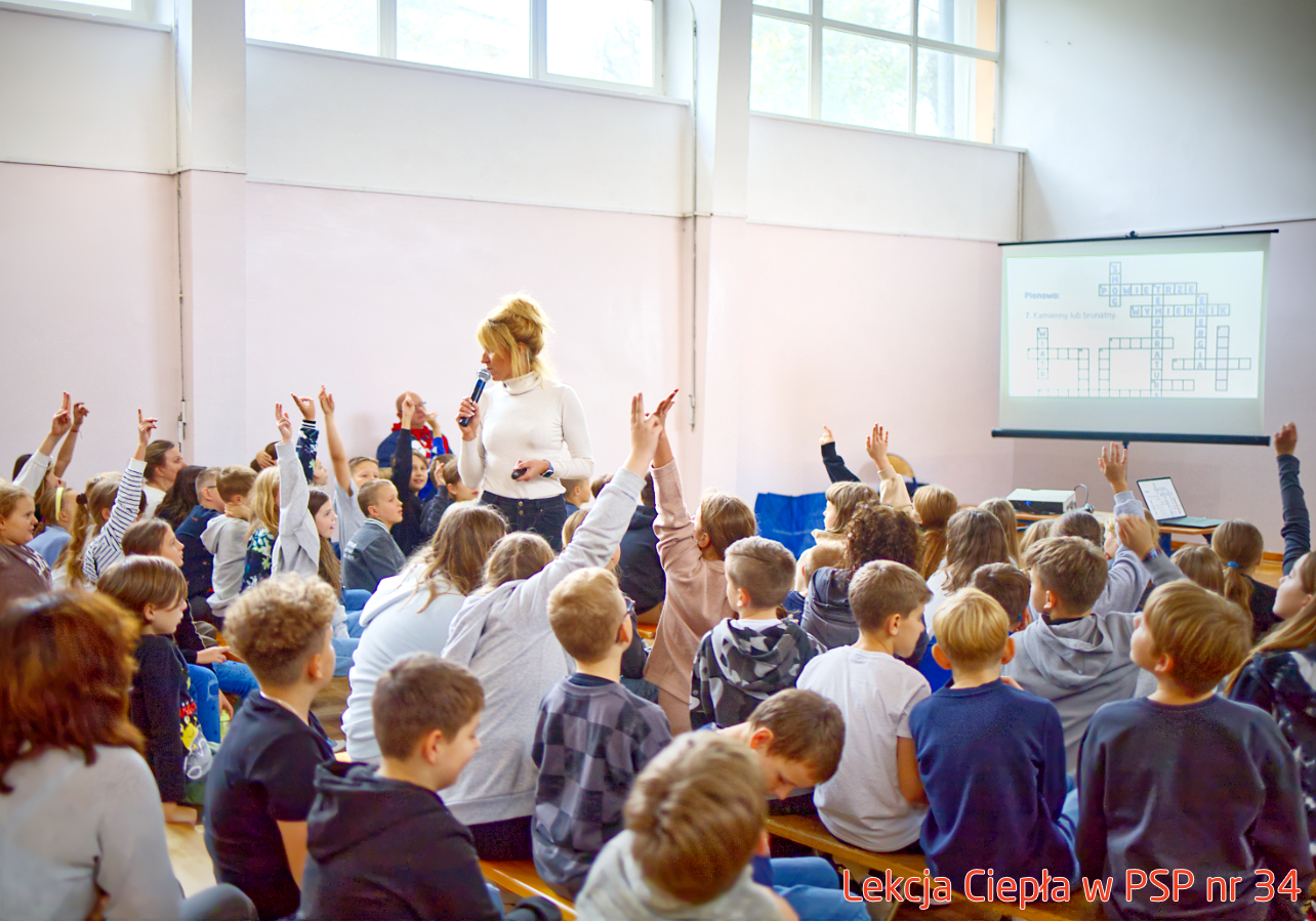 Pracownik „RADPEC” S.A. prowadzi lekcję ciepła dla uczniów klasy IV PSP nr 34. Stoi przed grupą uczniów. W tle znajduje się ekran z jednym ze slajdów prezentacji.